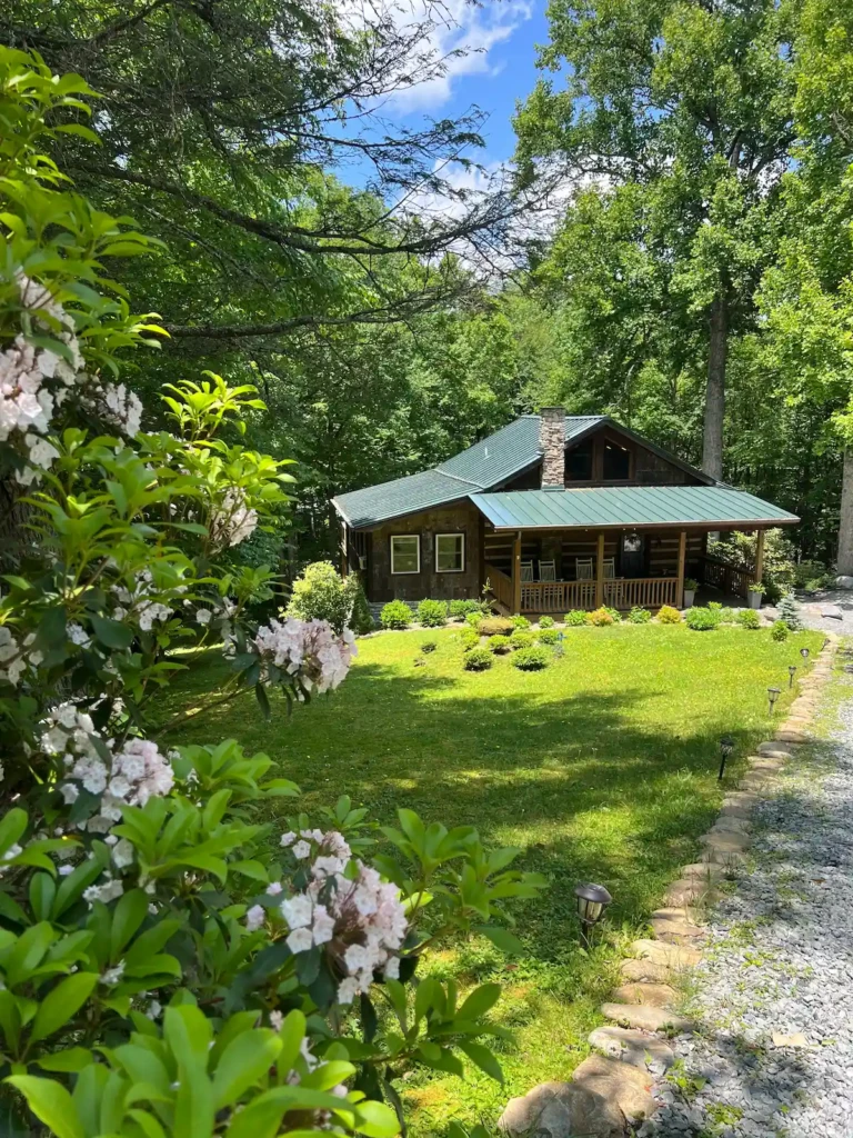 Hemlock Hill log cabin exterior surrounded by mountain laurel and trees in Blowing Rock NC